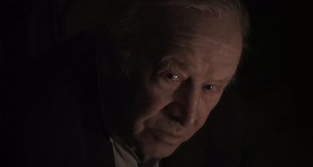 Movie still from “Inland Empire” (2006), directed by David Lynch – An old man with a white beard and a black suit; Close Up shot, Low angle