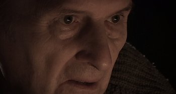 Movie still from “Inland Empire” (2006), directed by David Lynch – An older man with a sad look on his face; Extreme Close Up shot, Over the shoulder angle