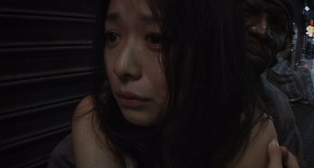 Movie still from “Inland Empire” (2006), directed by David Lynch – A woman with long dark brown hair sitting down; Close Up shot, Low angle