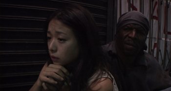 Movie still from “Inland Empire” (2006), directed by David Lynch – A young woman sitting next to a man in front of a wall; Close Up shot, Low angle