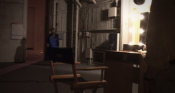 Movie still from “Inland Empire” (2006), directed by David Lynch – A man sitting in a chair in a room; Wide shot, Over the shoulder angle