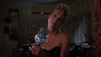 Movie still from “Innerspace” (1987), directed by Joe Dante – A woman in a black dress holding a cat mask; Close Up shot, Low angle