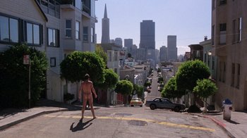 Movie still from “Innerspace” (1987), directed by Joe Dante – A naked man walking down a street in a city; Extreme Wide shot, Low angle