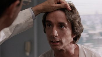 Movie still from “Innerspace” (1987), directed by Joe Dante – A man is getting his hair combed by a hand; Close Up shot, Over the shoulder angle