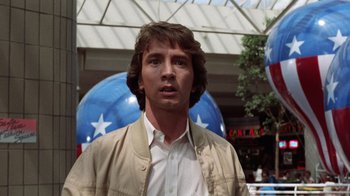 Movie still from “Innerspace” (1987), directed by Joe Dante – A man standing in front of a building with stars in the background; Medium shot, Low angle
