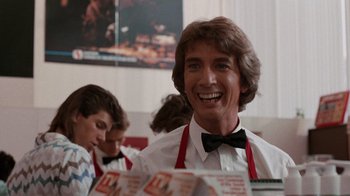 Movie still from “Innerspace” (1987), directed by Joe Dante – A man in a white shirt and black bow tie; Close Up shot, Over the shoulder angle
