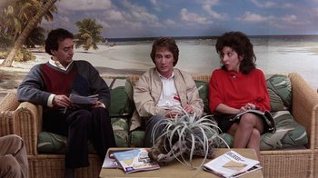 Movie still from “Innerspace” (1987), directed by Joe Dante – Three people sitting on a couch with a cat on a table; Medium shot, Over the shoulder angle