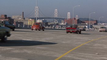 Movie still from “Innerspace” (1987), directed by Joe Dante – Cars are driving down a street near a bridge; Extreme Wide shot, High angle