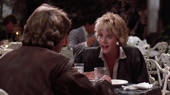 Movie still from “Innerspace” (1987), directed by Joe Dante – Two people sitting at a table talking to each other; Medium shot, Over the shoulder angle