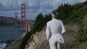 Movie still from “Innerspace” (1987), directed by Joe Dante – A man standing on a cliff looking at the golden gate bridge in san francisco; Wide shot, Low angle