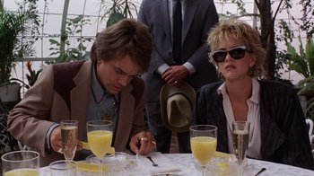 Movie still from “Innerspace” (1987), directed by Joe Dante – A man and a woman sitting at a dinner table with glasses of orange juice; Close Up shot, Low angle
