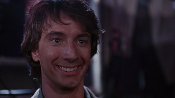Movie still from “Innerspace” (1987), directed by Joe Dante – A man smiling for the camera; Close Up shot, Over the shoulder angle