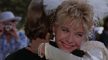 Movie still from “Innerspace” (1987), directed by Joe Dante – A woman hugging another woman in front of a building; Close Up shot, Over the shoulder angle