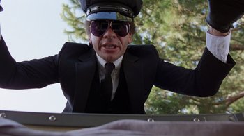 Movie still from “Innerspace” (1987), directed by Joe Dante – A man in a suit and tie wearing a hat; Medium shot, Low angle