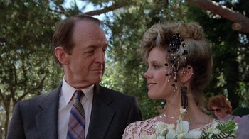 Movie still from “Innerspace” (1987), directed by Joe Dante – A man standing next to a woman wearing a suit and tie; Close Up shot, Over the shoulder angle