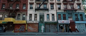 Movie still from “Inside Man” (2006), directed by Spike Lee – A man walking on the sidewalk in front of a building; Wide shot, Low angle