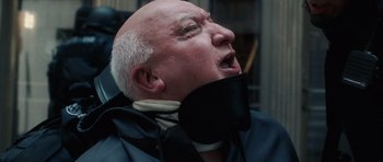 Movie still from “Inside Man” (2006), directed by Spike Lee – An older man wearing a neck brace; Close Up shot, Low angle