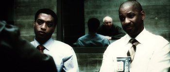 Movie still from “Inside Man” (2006), directed by Spike Lee – Two men are standing in front of a mirror; Close Up shot, Over the shoulder angle
