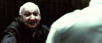 Movie still from “Inside Man” (2006), directed by Spike Lee – An older man with a shaved head and a goatee looking into the camera; Close Up shot, Over the shoulder angle