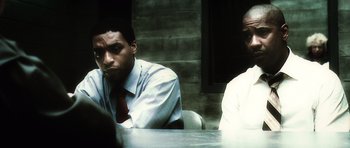 Movie still from “Inside Man” (2006), directed by Spike Lee – Two men sitting at a table in front of each other; Medium shot, Over the shoulder angle