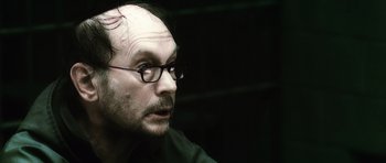 Movie still from “Inside Man” (2006), directed by Spike Lee – A person wearing glasses; Close Up shot, Over the shoulder angle