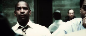 Movie still from “Inside Man” (2006), directed by Spike Lee – A man wearing a white shirt and a tie; Close Up shot, Over the shoulder angle