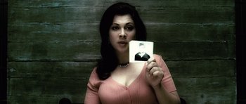Movie still from “Inside Man” (2006), directed by Spike Lee – A woman holding up an old picture of herself; Close Up shot, High angle