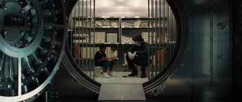 Movie still from “Inside Man” (2006), directed by Spike Lee – Two people sitting in a jail cell with a cell phone; Wide shot, Over the shoulder angle