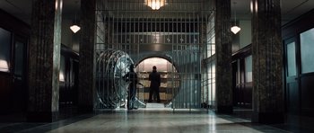 Movie still from “Inside Man” (2006), directed by Spike Lee – Two people in a room with a large metal door; Wide shot, Low angle