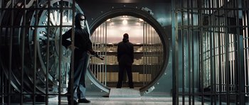 Movie still from “Inside Man” (2006), directed by Spike Lee – A man in a mask stands inside a large metal door; Wide shot, Low angle