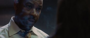 Movie still from “Inside Man” (2006), directed by Spike Lee – A person wearing a suit and tie; Close Up shot, Over the shoulder angle