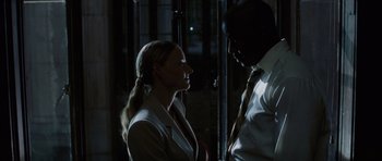 Movie still from “Inside Man” (2006), directed by Spike Lee – A woman and a man are talking in a dark room; Medium shot, Low angle