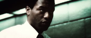 Movie still from “Inside Man” (2006), directed by Spike Lee – A person wearing a suit and tie; Close Up shot, Low angle
