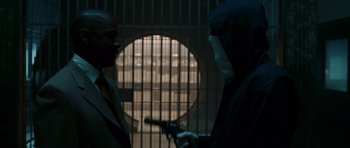 Movie still from “Inside Man” (2006), directed by Spike Lee – Two men in a dark room holding a gun; Medium shot, Over the shoulder angle