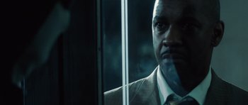 Movie still from “Inside Man” (2006), directed by Spike Lee – A person wearing a suit and tie; Close Up shot, Over the shoulder angle