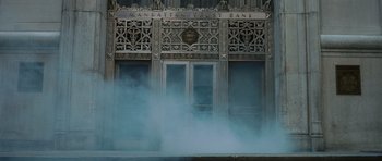 Movie still from “Inside Man” (2006), directed by Spike Lee – A building that has some smoke coming out of it's windows; Wide shot, Low angle