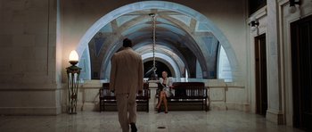 Movie still from “Inside Man” (2006), directed by Spike Lee – A man and a woman sitting on a bench in a building; Wide shot, Low angle