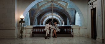 Movie still from “Inside Man” (2006), directed by Spike Lee – A man and a woman sitting on a wooden bench; Wide shot, Low angle