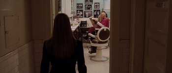 Movie still from “Inside Man” (2006), directed by Spike Lee – A woman standing in front of a man sitting in a barber chair; Medium shot, Over the shoulder angle