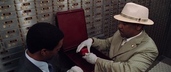 Movie still from “Inside Man” (2006), directed by Spike Lee – A man in white gloves is holding a red box; Close Up shot, High angle