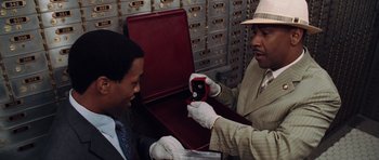 Movie still from “Inside Man” (2006), directed by Spike Lee – A man is holding a cell phone while another man is looking at it; Close Up shot, High angle