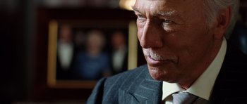 Movie still from “Inside Man” (2006), directed by Spike Lee – An older man wearing a suit and tie; Close Up shot, Over the shoulder angle