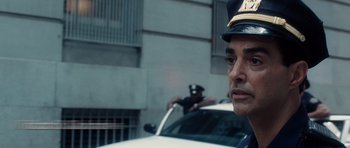 Movie still from “Inside Man” (2006), directed by Spike Lee – A police officer standing in front of a white car; Close Up shot, Over the shoulder angle