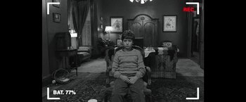 Movie still from “Insidious: Chapter 2” (2013), directed by James Wan – A young boy sitting in a chair in a living room; Wide shot, High angle