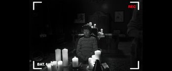 Movie still from “Insidious: Chapter 2” (2013), directed by James Wan – A man sitting in a chair in front of a table of candles; Medium shot, High angle