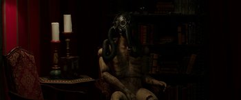 Movie still from “Insidious: Chapter 2” (2013), directed by James Wan – A man sitting in a chair wearing a gas mask; Medium shot, High angle