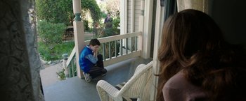 Movie still from “Insidious: Chapter 2” (2013), directed by James Wan – A young boy sitting on a porch looking at a woman; Wide shot, Over the shoulder angle