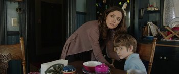 Movie still from “Insidious: Chapter 2” (2013), directed by James Wan – A woman standing next to a child at a table; Medium shot, Over the shoulder angle