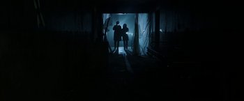 Movie still from “Insidious: Chapter 2” (2013), directed by James Wan – Two people are standing in a dark room; Wide shot, Low angle