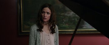 Movie still from “Insidious: Chapter 2” (2013), directed by James Wan – A woman standing in front of a piano in front of a painting; Close Up shot, Over the shoulder angle